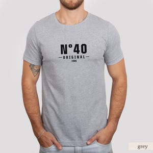 May include: A heather grey short-sleeved t-shirt featuring black text on the chest that reads N&deg;40 ORIGINAL 1986. The garment has a crew neckline and a standard fit, constructed from a soft, lightweight fabric with a visible heathered texture.