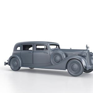 Può includere: Un'auto d'epoca argentata con una griglia cromata e un ornamento a forma di uccello sul cofano. L'auto ha quattro porte e una ruota di scorta sul retro.