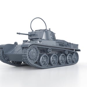 Op de afbeelding: Een grijs model van een tank met een geschutstoren, rupsbanden en wielen. De tank heeft een gebogen antenne en staat tegen een witte achtergrond. De tank is een gedetailleerde replica van een militair voertuig.