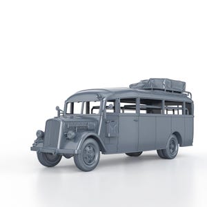 May include: A grey model of a vintage bus with a luggage rack on the roof. The bus has a large windscreen and a rounded front end. The bus is on a white background.