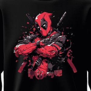 Puede incluir: Sudadera negra con una ilustraci&oacute;n roja y negra de un personaje de c&oacute;mic. El personaje lleva una m&aacute;scara y un traje rojos, con los brazos cruzados y dos espadas detr&aacute;s. Se ven salpicaduras de pintura roja.