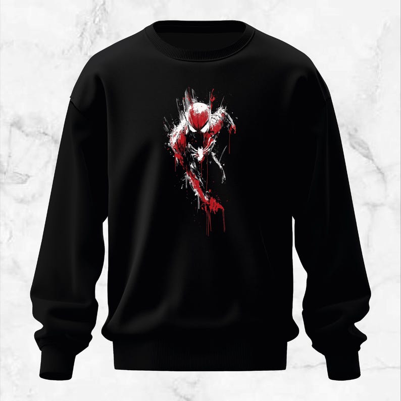Puede incluir: Sudadera negra con un dise&ntilde;o gr&aacute;fico rojo y blanco de un superh&eacute;roe en movimiento. El dise&ntilde;o utiliza un efecto de salpicadura de pintura. Cuello redondo y mangas largas.