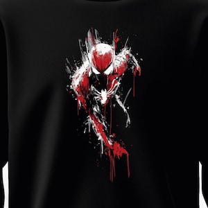 Puede incluir: Sudadera negra con una impactante representaci&oacute;n art&iacute;stica de Spider-Man. El dise&ntilde;o utiliza audaces pinceladas rojas y blancas sobre un fondo negro, creando un efecto visual din&aacute;mico. El superh&eacute;roe se representa en una pose de carrera.