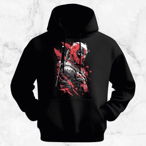 Peut inclure: Sweat &agrave; capuche noir avec un graphisme rouge et noir d'un personnage masqu&eacute; avec une &eacute;p&eacute;e. Le design a un effet aquarelle, avec des &eacute;claboussures de peinture rouge ajoutant au look dynamique. Le sweat &agrave; capuche a une poche avant et une capuche &agrave; cordon.