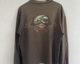 May include: A long-sleeved, brown shirt with a graphic on the back. The graphic features a mountain scene with the word "BEAR" at the bottom. The shirt has a crew neck and long sleeves.