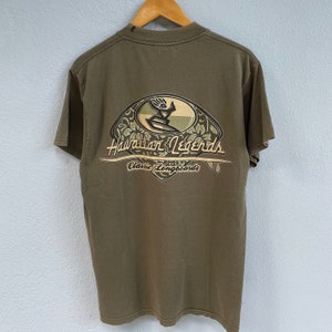 May include: A green t-shirt with a graphic print of a surfer riding a wave. The graphic includes the text "Hawaiian Legends Classic Longboards".