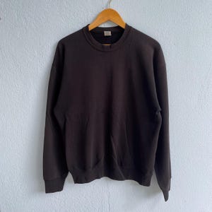 Peut inclure: Un sweat-shirt à col rond de couleur marron foncé à manches longues.