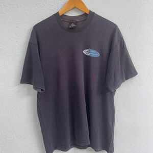 Op de afbeelding: Een donkergrijs T-shirt met een blauw en wit logo met de tekst "Local Motion".