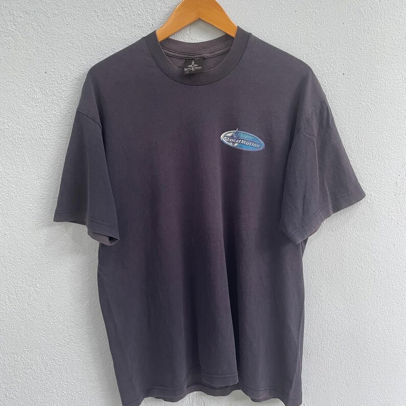 Op de afbeelding: Een donkergrijs T-shirt met een blauw en wit logo met de tekst "Local Motion".