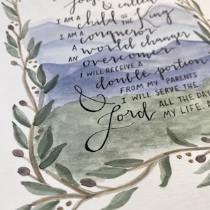 May include: Watercolor art print with calligraphy text. The text reads "I am forgiven & called, I am a child of the King, I am a conqueror, a world changer, an overcomer." The print is framed by a green and brown floral wreath. The background features blue and green watercolor washes.