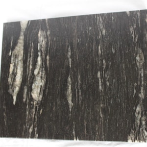 Könnte beinhalten: Schwarze Granitplatte mit weißen und grauen Adern. Die Adern ähneln Holzmaserung.