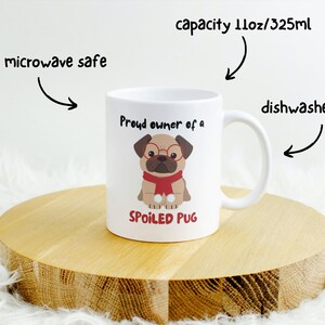 K&ouml;nnte beinhalten: Wei&szlig;e Keramiktasse mit einem Mops, der eine Brille und einen roten Schal tr&auml;gt. Auf der Tasse steht "Proud owner of a SPOILED PUG". Sie hat ein Fassungsverm&ouml;gen von 325 ml und ist mikrowellen- und sp&uuml;lmaschinenfest.