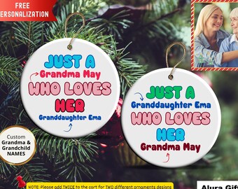 May include: Two white ceramic Christmas ornaments with gold string hangers. Each ornament has a different design with the text "JUST A Grandma May WHO LOVES HER Granddaughter Ema" and "JUST A Granddaughter Ema WHO LOVES HER Grandma May".