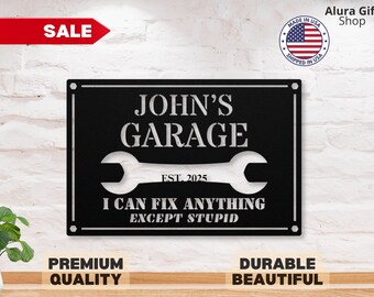 May include: Black metal sign with white text that reads "JOHN'S GARAGE EST. 2025 I CAN FIX ANYTHING EXCEPT STUPID". The sign features a wrench graphic.