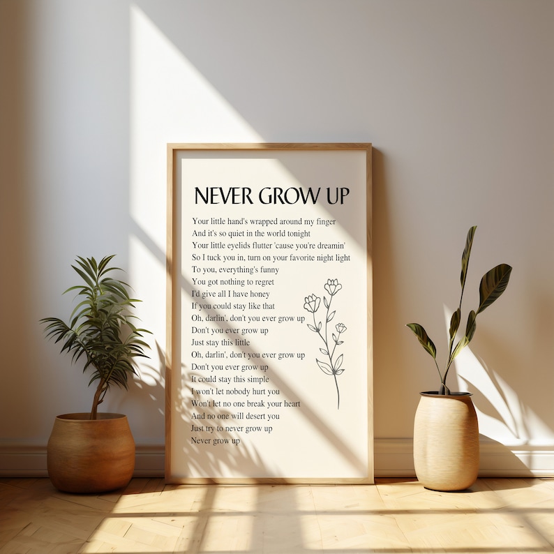 May include: A white framed print with black text that reads "Never Grow Up" and a simple line drawing of a flower. The text is a poem about staying young at heart.
