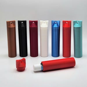 May include: Eight small, cylindrical containers with different colored lids and bodies. The containers are made of plastic and have a small hole at the top. One container is open, revealing a white stick inside.