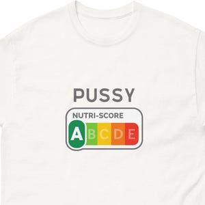 Op de afbeelding: Een wit T-shirt met korte mouwen met het woord PUSSY in donkergrijs gedrukt boven een Nutri-Score grafische afbeelding. De afbeelding toont een horizontale schaal met de letters A, B, C, D en E, waarbij de letter A in een groen vak is gemarkeerd.