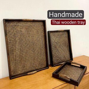 May include: Three handmade wooden trays with woven patterns. The largest tray is brown with a woven pattern and the text "Handmade Thai wooden tray" is printed on a white background.