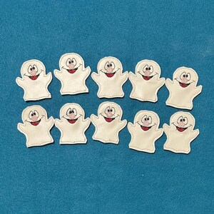 May include: Ten white ghost-shaped appliqués with smiling faces and red mouths are arranged on a teal background. Each ghost has a stitched outline and a friendly expression, perfect for Halloween crafts or decorations.