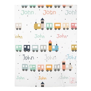May include: A white baby blanket with a colorful train pattern. The train is made up of multiple cars in different colors, including yellow, blue, green, and pink. The blanket has black polka dots and the name "John" repeated throughout.