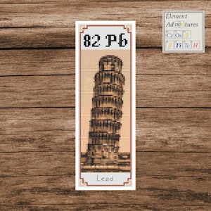 May include: A bookmark featuring a cross-stitch design of the Leaning Tower of Pisa. The bookmark has the text "82 Pb" at the top and "Lead" at the bottom. The background is a light peach color.