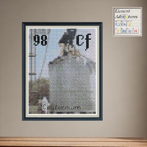 May include: Framed cross-stitch art featuring the element Californium (Cf) with atomic number 98. The artwork depicts a stylized image of a building or structure, with the element's name and symbol. The frame is black.
