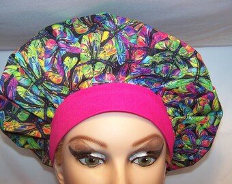 May include: A colorful surgical scrub hat with a pink trim. The hat features a dragonfly print with a black background.