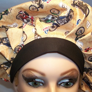 May include: A tan and black scrub hat with a vintage motorcycle print. The hat has a black elastic band and a black fabric tie.