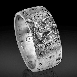 May include: A silver ring with an elaborate design. The ring showcases a detailed relief of a figure and is decorated with various symbols and markings. The ring has a wide band and a polished finish, suitable for a unique accessory.
