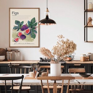 Op de afbeelding: Een ingelijste kunstdruk met een aquarel illustratie van vijgen. Het kunstwerk toont hele en gesneden vijgen met groene bladeren, en het woord "Figs" bovenaan. De tekst "Grown with love from the Mediterranean!" staat onderaan.