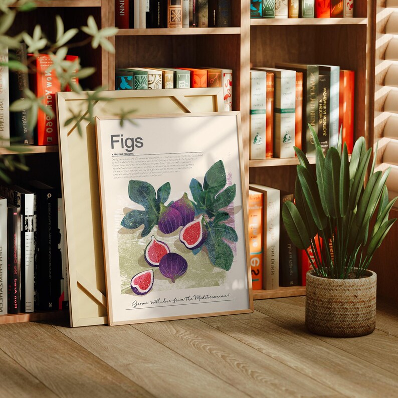 Op de afbeelding: Een ingelijste kunstdruk met een illustratie van vijgen, met het woord "Figs" bovenaan. Het kunstwerk toont hele en gesneden vijgen, groene bladeren en tekst. De print leunt tegen een boekenplank vol boeken.
