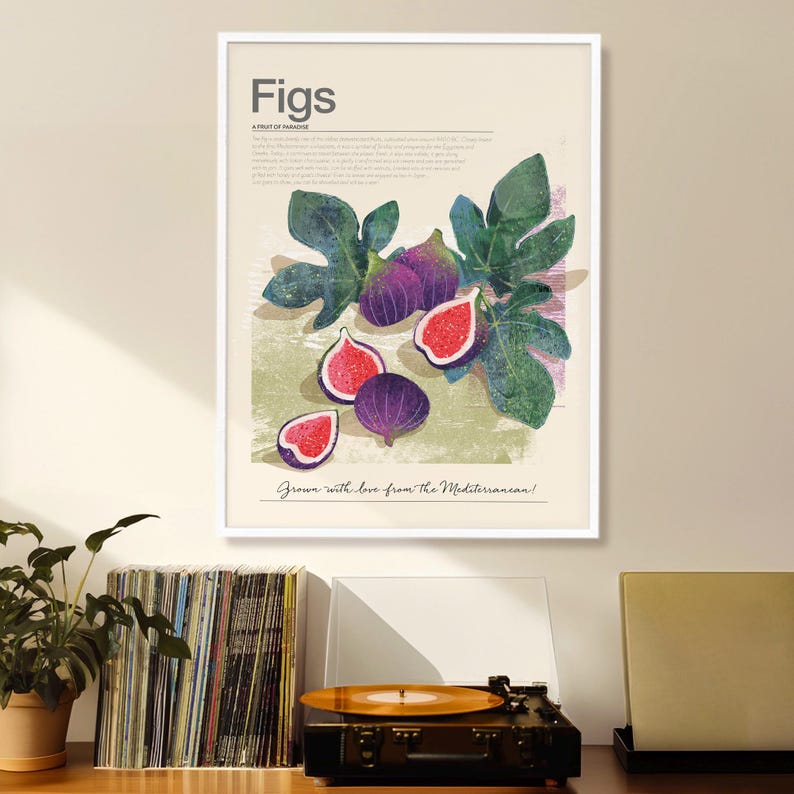 Op de afbeelding: Een ingelijste kunstdruk met een botanische illustratie van vijgen. Het kunstwerk toont hele en gesneden vijgen in paars en rood, met groene bladeren. De tekst "Figs" en "Grown with love from the Mediterranean!" zijn ook opgenomen.
