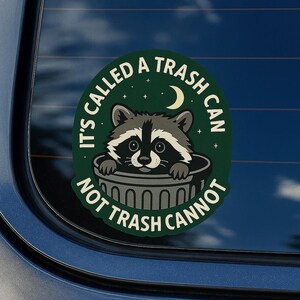 May include: A circular sticker with a raccoon peeking out of a trash can. The sticker is green with white text that reads "IT'S CALLED A TRASH CAN NOT TRASH CANNOT". A crescent moon and stars are also featured.