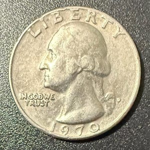 Puede incluir: Una moneda de cuarto de dólar de plata de 1970 con el perfil de una persona, la palabra "LIBERTY" en la parte superior y "IN GOD WE TRUST" debajo. Moneda de curso legal de Estados Unidos.