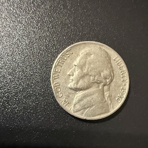 Op de afbeelding: Een zilveren munt met het profiel van een man, de woorden "IN GOD WE TRUST" en "LIBERTY 1940" zijn zichtbaar. De munt ligt op een donkere ondergrond.