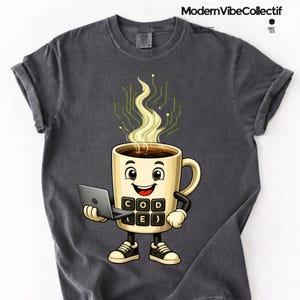 May include: A charcoal gray t-shirt featuring a cartoon coffee mug character holding a laptop. The mug has a face, arms, legs, and a keypad on its front with the text "CODE". Steam rising from the mug forms a green circuit board pattern.