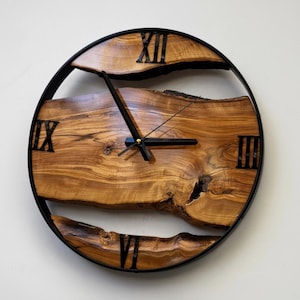 Handmade olive wood wall clock with natural live edge design and black metal frame.