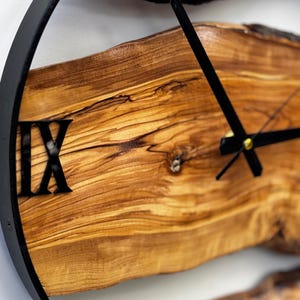 Natural live edge olive wood clock displayed against a clean white wall.