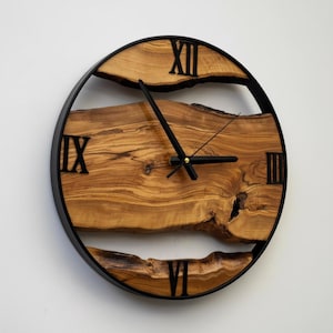 Close-up of olive wood grain patterns and Roman numeral details on wall clock.