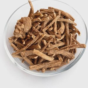 May include: A clear glass bowl filled with a collection of dried, light brown woody root pieces. The roots are irregular in shape, varying in length and thickness, with a rough, fibrous texture. One larger, rounded root segment sits on the left side.
