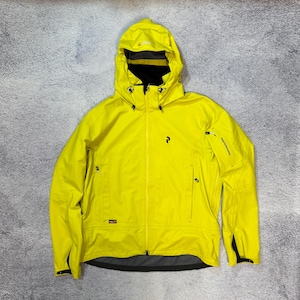 May include: Vibrant yellow hooded jacket with a full zip. The jacket has a black lining in the hood and a small logo on the chest. The sleeves have black cuffs. The jacket is designed for outdoor activities and is suitable for various weather conditions.