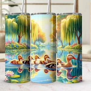 May include: A set of three stainless steel tumblers with a colorful design featuring a pond scene with ducks and weeping willow trees. The tumblers are perfect for enjoying your favorite beverages.