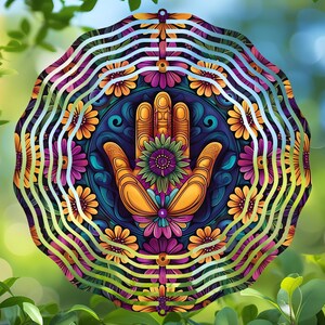 Peut inclure: Un mobile en métal coloré avec un motif de main au centre. La main est entourée d'un mandala de fleurs dans des tons de jaune, rose, violet et bleu. Le mobile a un design en couches avec des cercles concentriques.