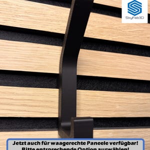 Auf dem Bild ist ein einzelner Doppelhaken in schwarz abgebildet, welcher auf einem horizontal montierten Akustikpaneel angebracht ist. Unten steht als Text: "Jetzt auch für waagerechte Paneele verfügbar! Bitte entsprechende Option auswählen!"