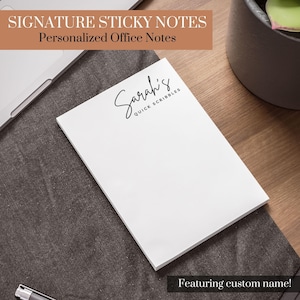 May include: White sticky note pad with the text "Sarah's Quick Scribbles" in black script. The pad is on a gray surface, with the text "Signature Sticky Notes" and "Personalized Office Notes" at the top. The bottom of the image reads "Featuring custom name!"