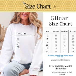 May include: White crewneck sweatshirt with a size chart. The chart shows measurements in inches for width, length, and sleeve length for sizes S to 3XL. The text reads "Gildan Size Chart" and "Crewneck Sweatshirt & Hoodie".