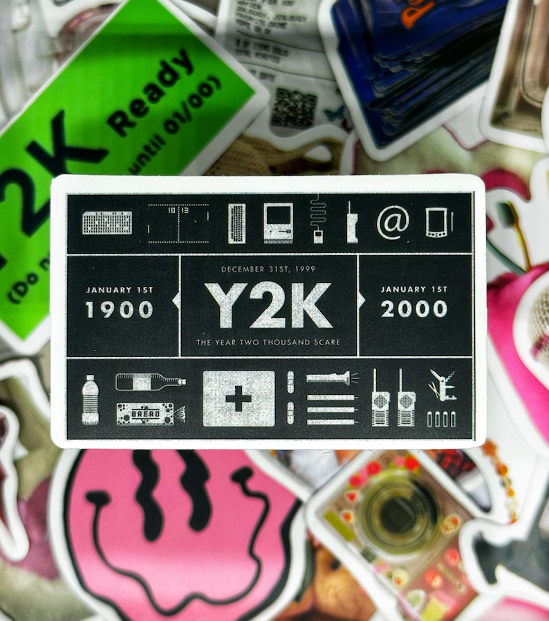 May include: A white sticker with black text and icons depicting the Y2K bug. The sticker reads "JANUARY 1ST 1900" and "JANUARY 1ST 2000" with "DECEMBER 31ST, 1999 Y2K THE YEAR TWO THOUSAND SCARE" in the centre. The icons include a computer monitor, a phone, an email symbol, a first aid kit, a set of three lines, a walkie talkie, and a padlock.