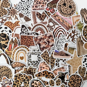 May include: A selection of leopard print stickers in diverse forms. Designs include hearts, bows, shoes, rainbows, perfume bottles, and a smiley face. The stickers feature brown and black spots on a tan background.