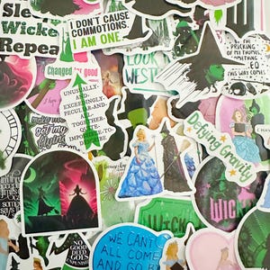 May include: A collection of colorful stickers featuring characters and quotes from the musical "Wicked." The stickers include images of the Wicked Witch of the West, Glinda, and various quotes like "Defying Gravity" and "I don't cause commotions."