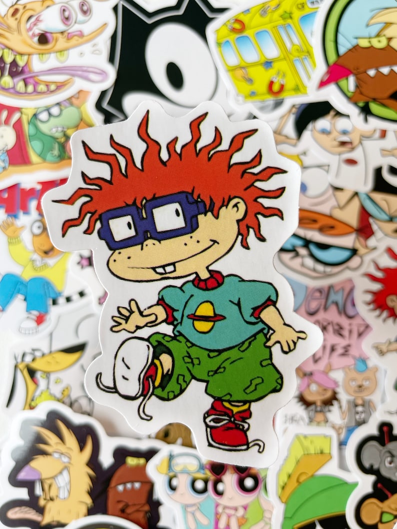 May include: A sticker featuring a cartoon character with red hair, wearing blue glasses, a green shirt with a yellow planet, and green camouflage pants. The character is running and kicking their leg up.